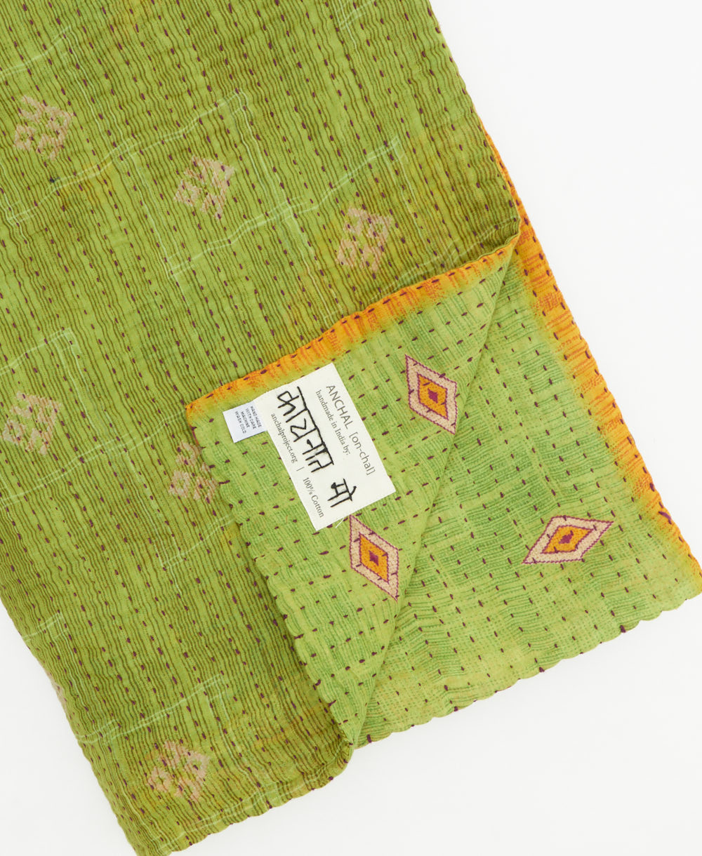 kantha quilt throw with a tag featuring the hand-stitched signature of the maker