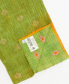 kantha quilt throw with a tag featuring the hand-stitched signature of the maker