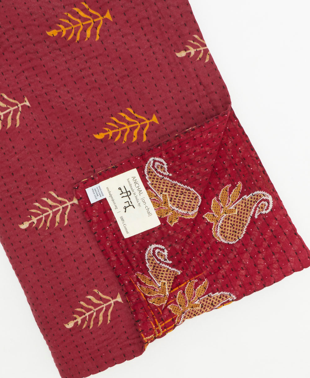 kantha quilt throw with a tag featuring the hand-stitched signature of the maker