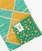 kantha quilt throw with a tag featuring the hand-stitched signature of the maker