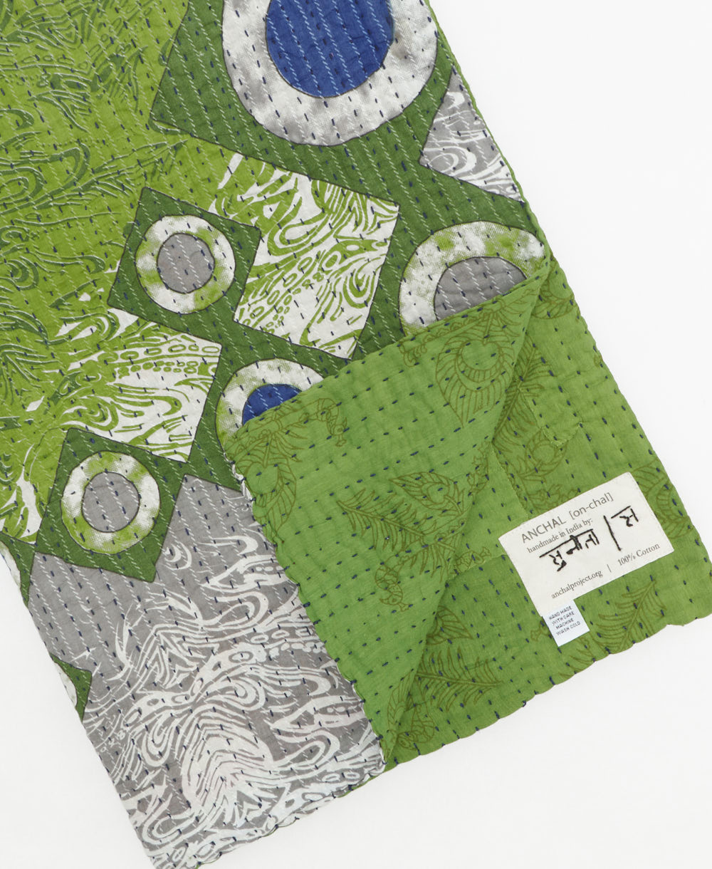kantha quilt throw with a tag featuring the hand-stitched signature of the maker