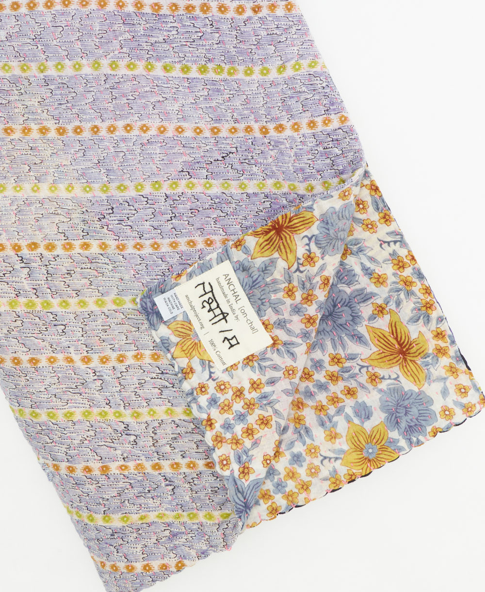kantha quilt throw with a tag featuring the hand-stitched signature of the maker
