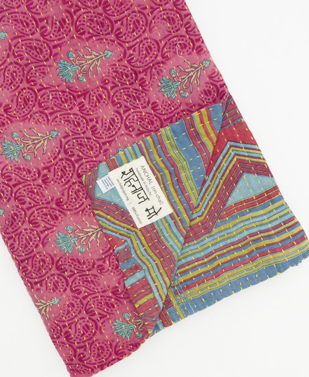kantha quilt throw with a tag featuring the hand-stitched signature of the maker
