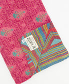 kantha quilt throw with a tag featuring the hand-stitched signature of the maker