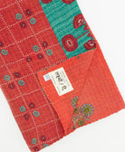 kantha quilt throw with a tag featuring the hand-stitched signature of the maker