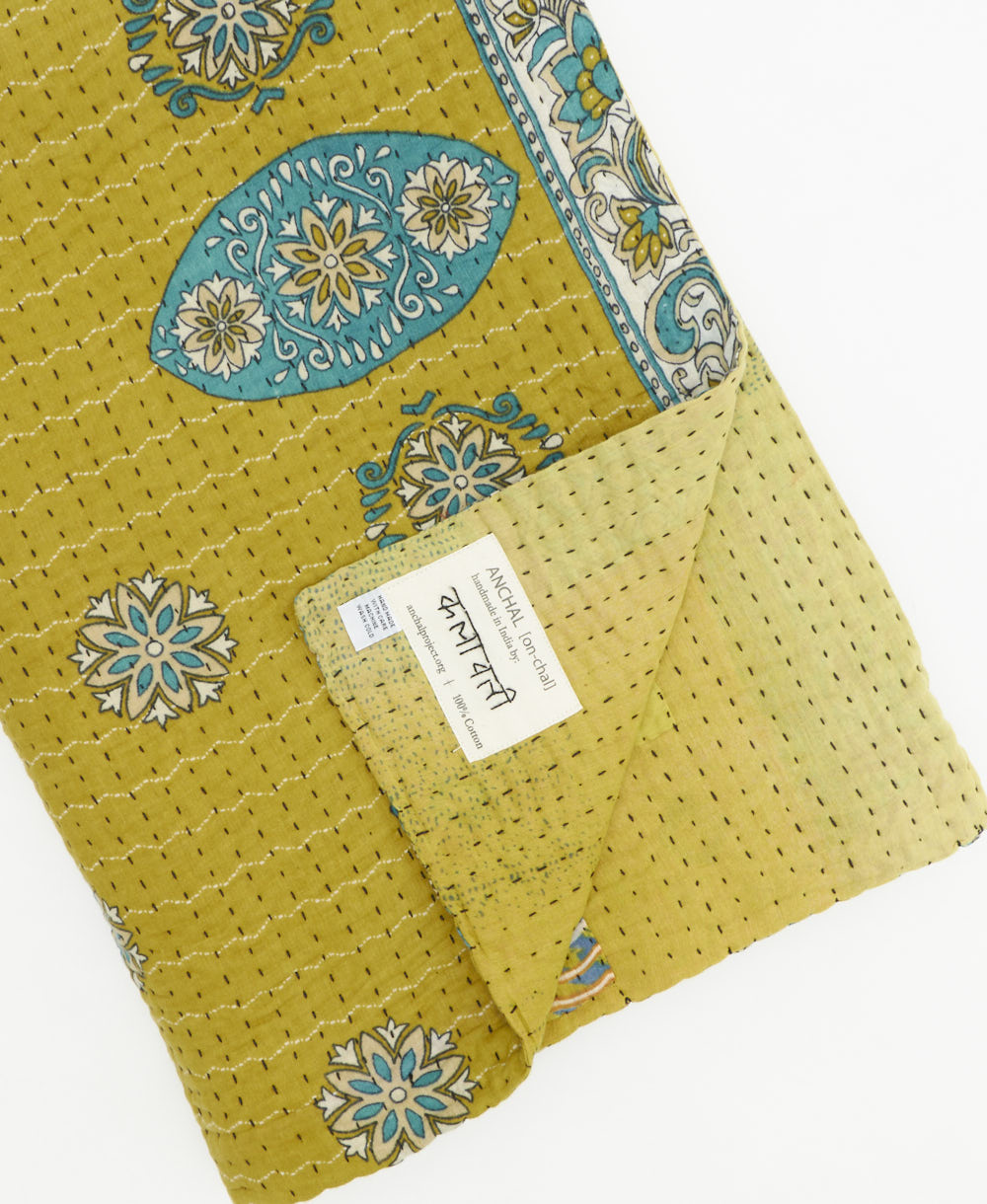 kantha quilt throw with a tag featuring the hand-stitched signature of the maker