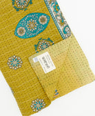 kantha quilt throw with a tag featuring the hand-stitched signature of the maker