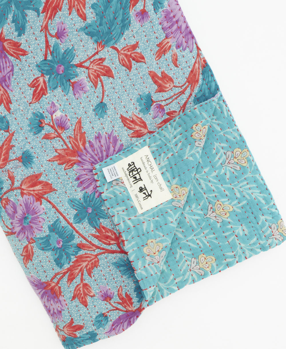 kantha quilt throw with a tag featuring the hand-stitched signature of the maker