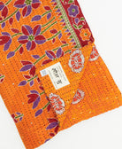 kantha quilt throw with a tag featuring the hand-stitched signature of the maker
