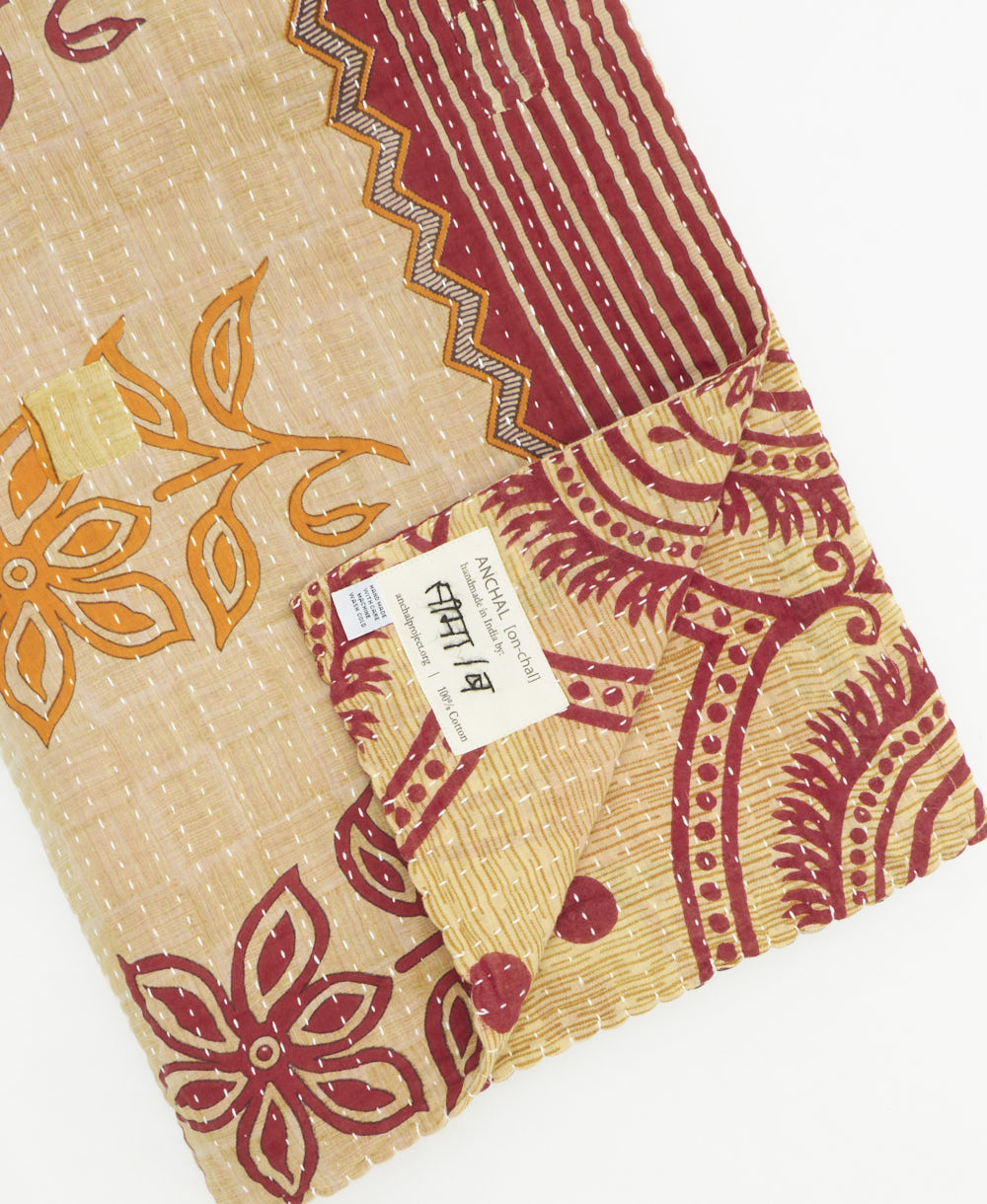 kantha quilt throw with a tag featuring the hand-stitched signature of the maker