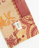 kantha quilt throw with a tag featuring the hand-stitched signature of the maker