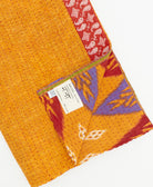 kantha quilt throw with a tag featuring the hand-stitched signature of the maker