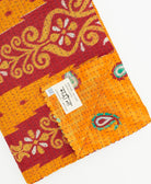 kantha quilt throw with a tag featuring the hand-stitched signature of the maker