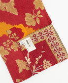 kantha quilt throw with a tag featuring the hand-stitched signature of the maker