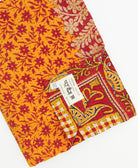 kantha quilt throw with a tag featuring the hand-stitched signature of the maker