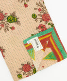 kantha quilt throw with a tag featuring the hand-stitched signature of the maker