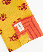 kantha quilt throw with a tag featuring the hand-stitched signature of the maker