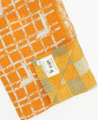 kantha quilt throw with a tag featuring the hand-stitched signature of the maker