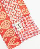 kantha quilt throw with a tag featuring the hand-stitched signature of the maker