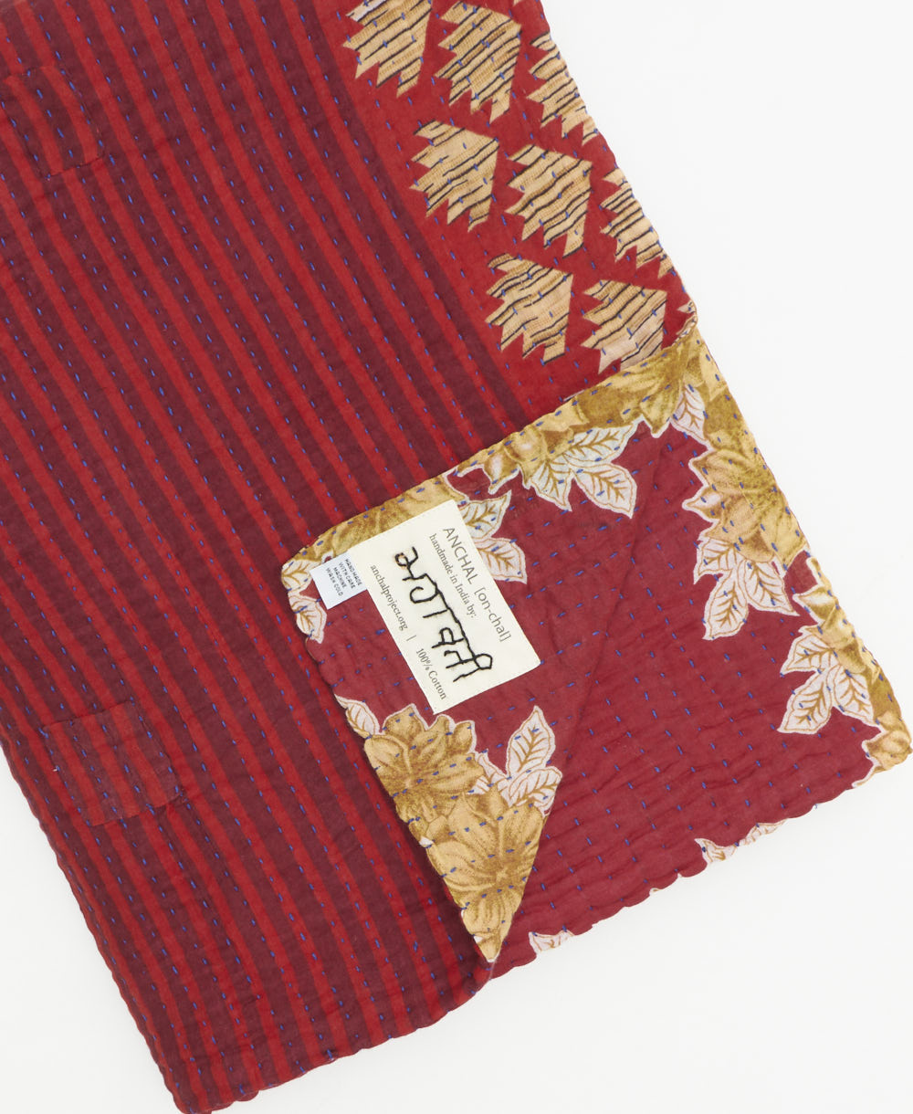 kantha quilt throw with a tag featuring the hand-stitched signature of the maker