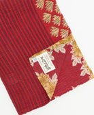 kantha quilt throw with a tag featuring the hand-stitched signature of the maker