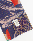 kantha quilt throw with a tag featuring the hand-stitched signature of the maker