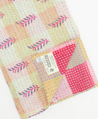 kantha quilt throw with a tag featuring the hand-stitched signature of the maker