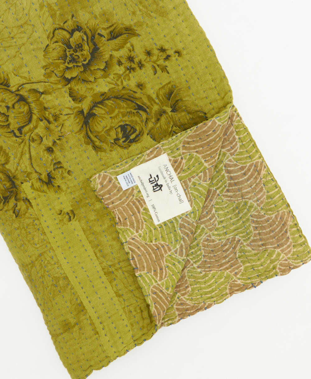 kantha quilt throw with a tag featuring the hand-stitched signature of the maker