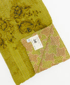 kantha quilt throw with a tag featuring the hand-stitched signature of the maker