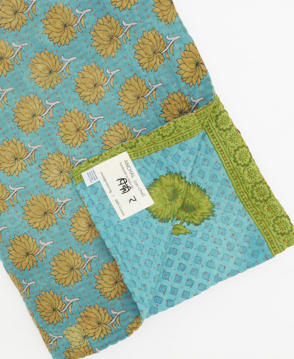 kantha quilt throw with a tag featuring the hand-stitched signature of the maker