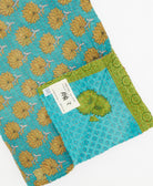 kantha quilt throw with a tag featuring the hand-stitched signature of the maker