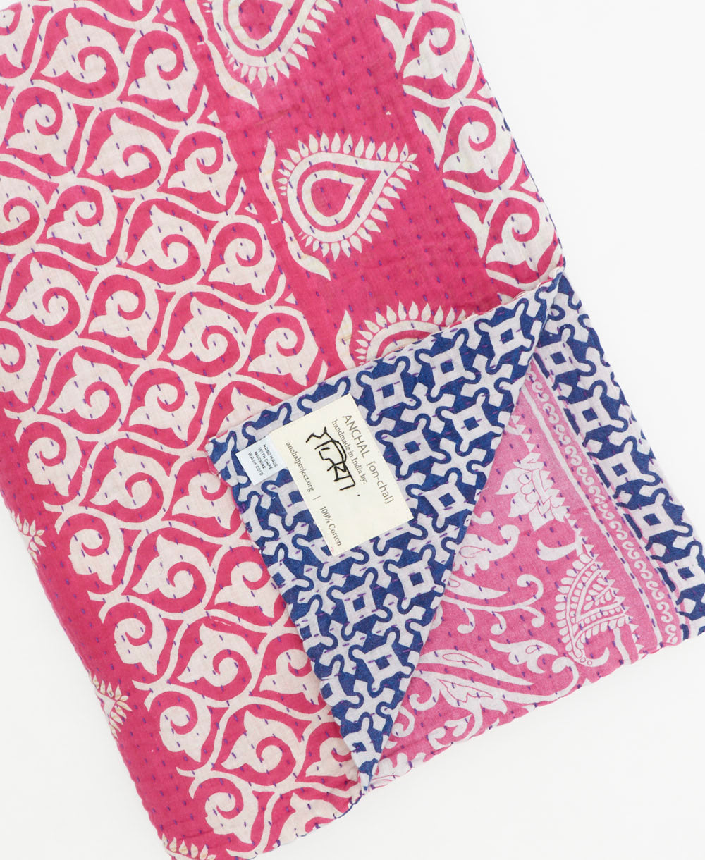 kantha quilt throw with a tag featuring the hand-stitched signature of the maker