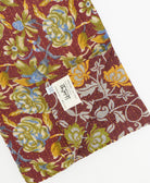 kantha quilt throw with a tag featuring the hand-stitched signature of the maker