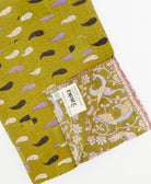 kantha quilt throw with a tag featuring the hand-stitched signature of the maker