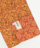 kantha quilt throw with a tag featuring the hand-stitched signature of the maker