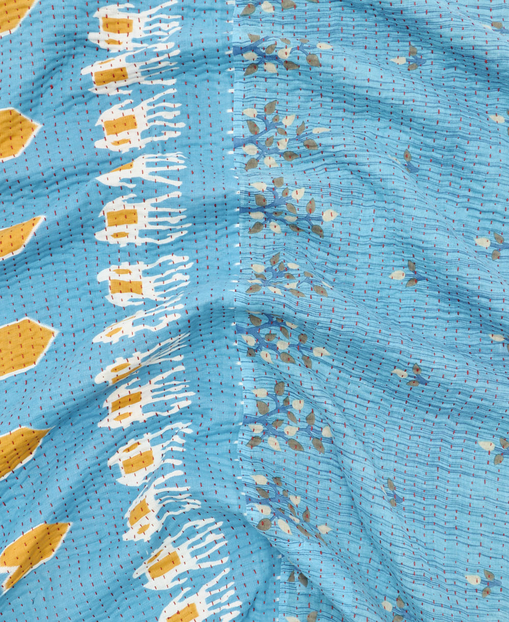 kantha quilt throw with a tag featuring the hand-stitched signature of the maker