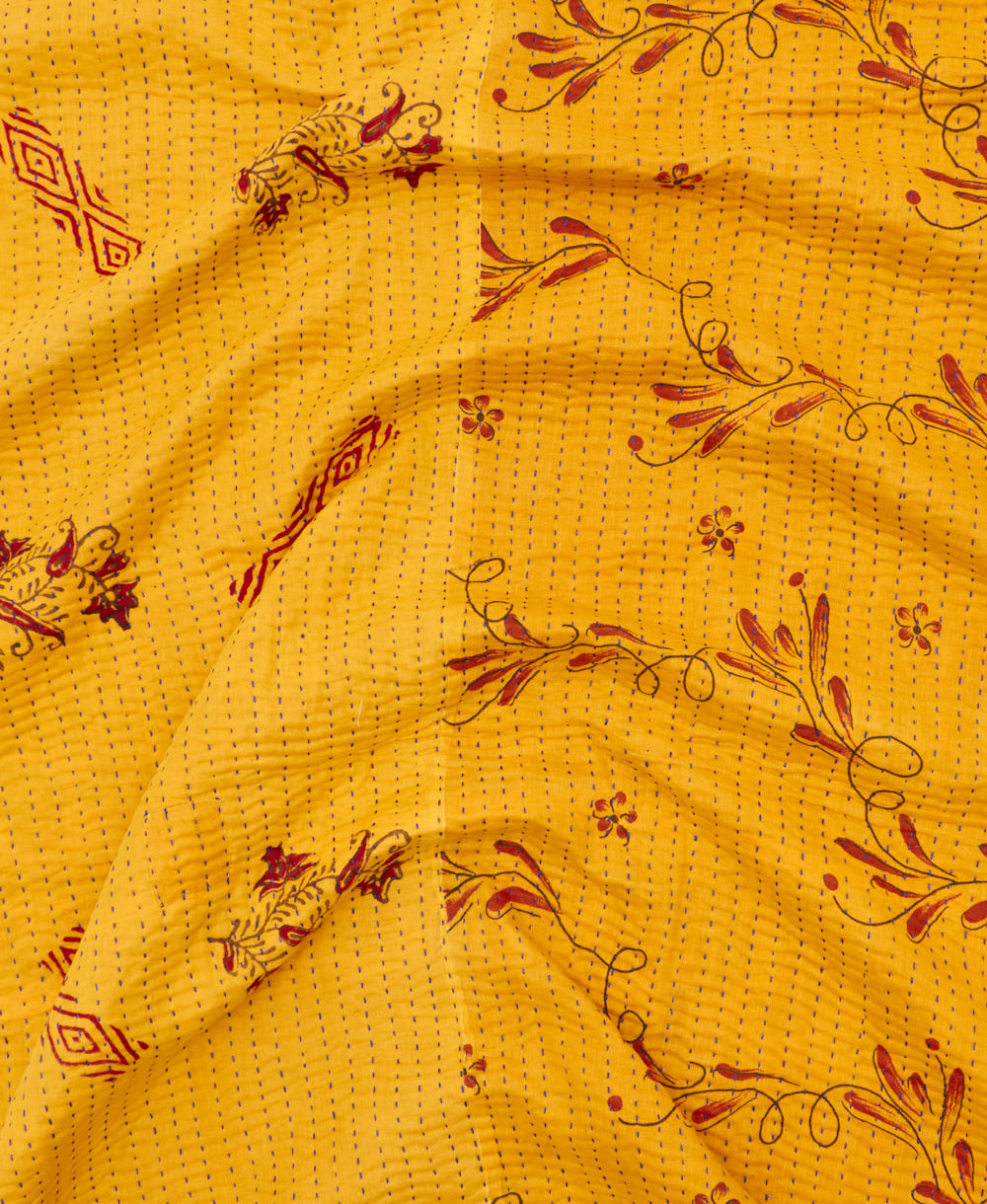 kantha quilt throw with a tag featuring the hand-stitched signature of the maker