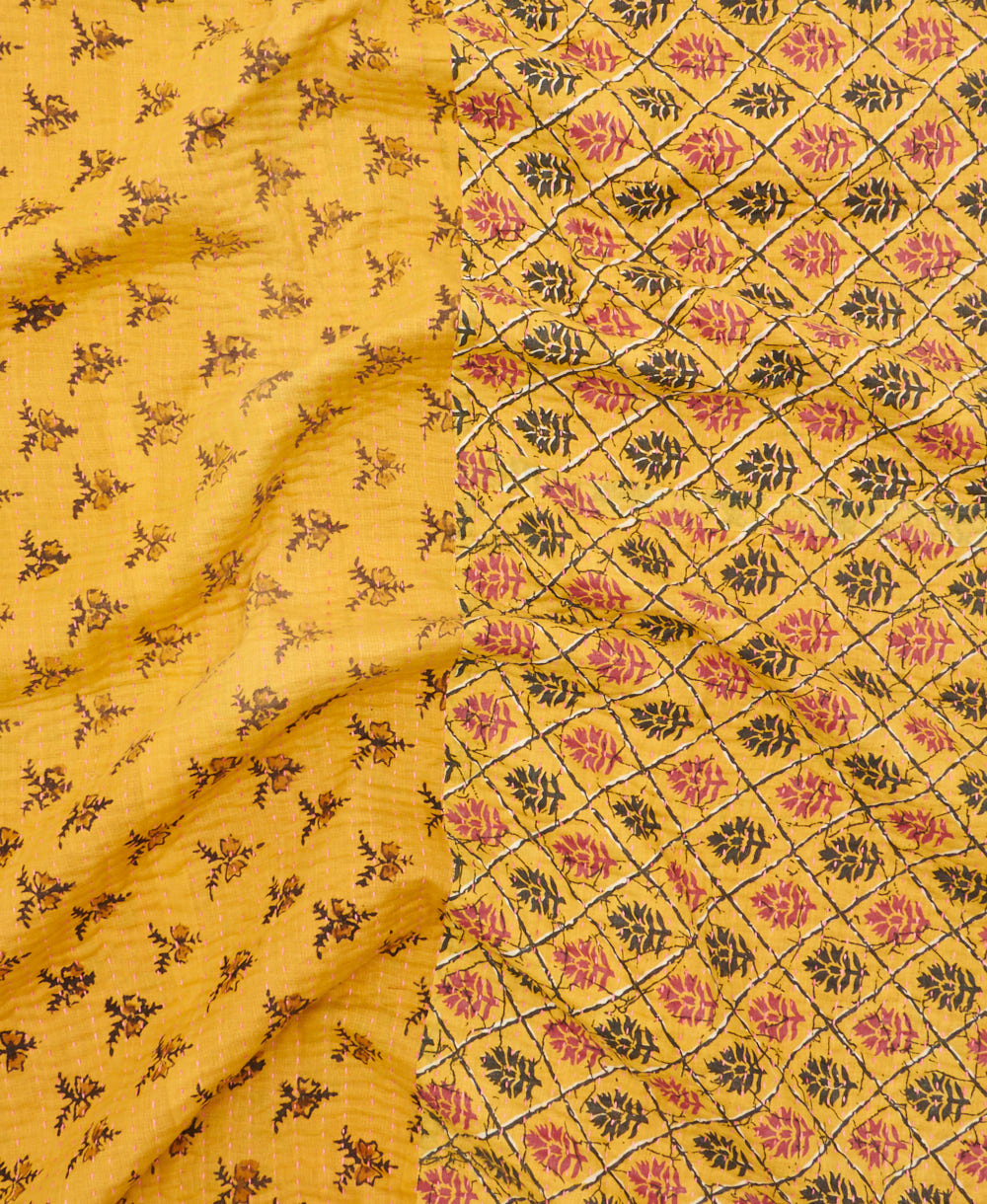 kantha quilt throw with a tag featuring the hand-stitched signature of the maker