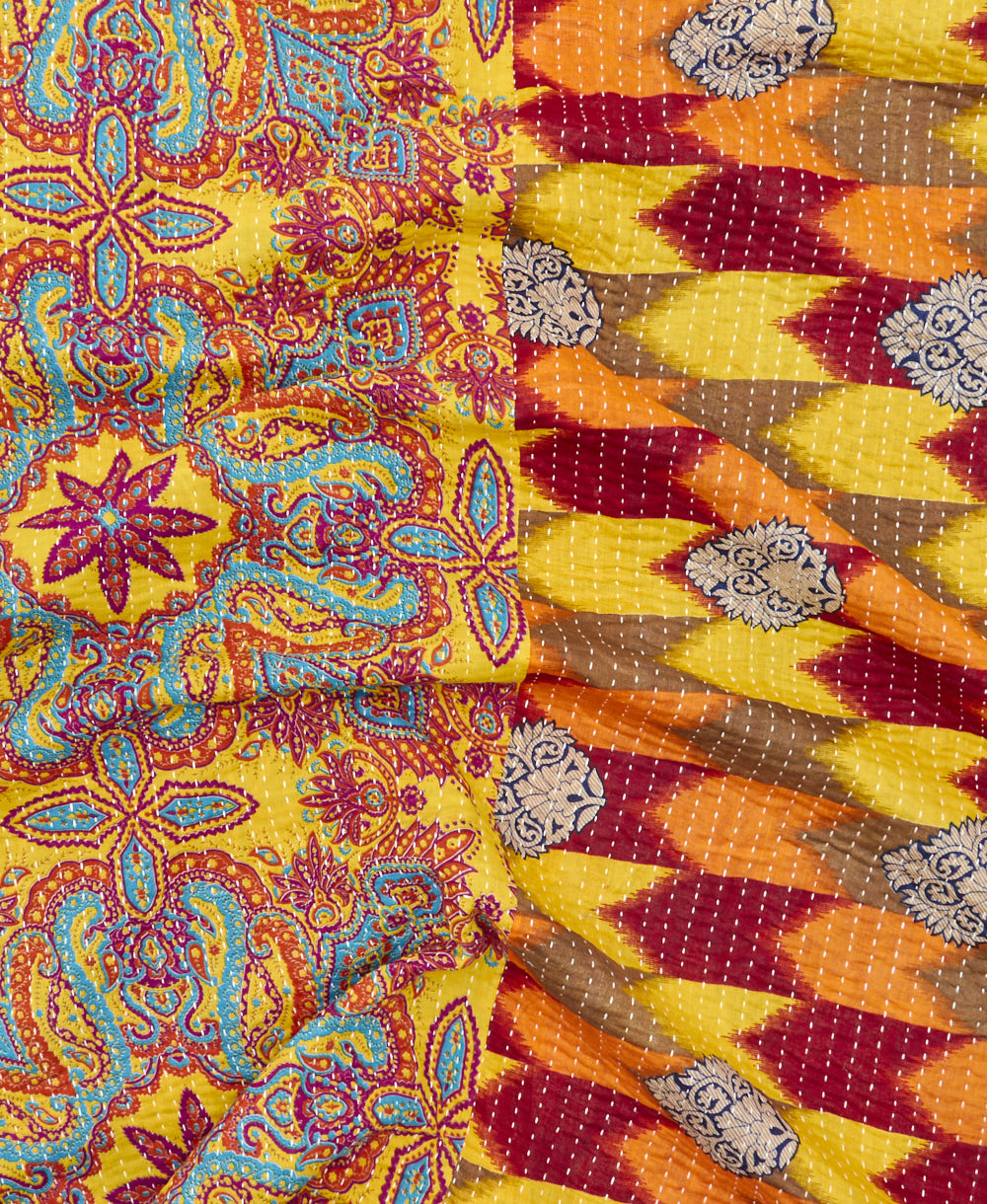 kantha quilt throw with a tag featuring the hand-stitched signature of the maker