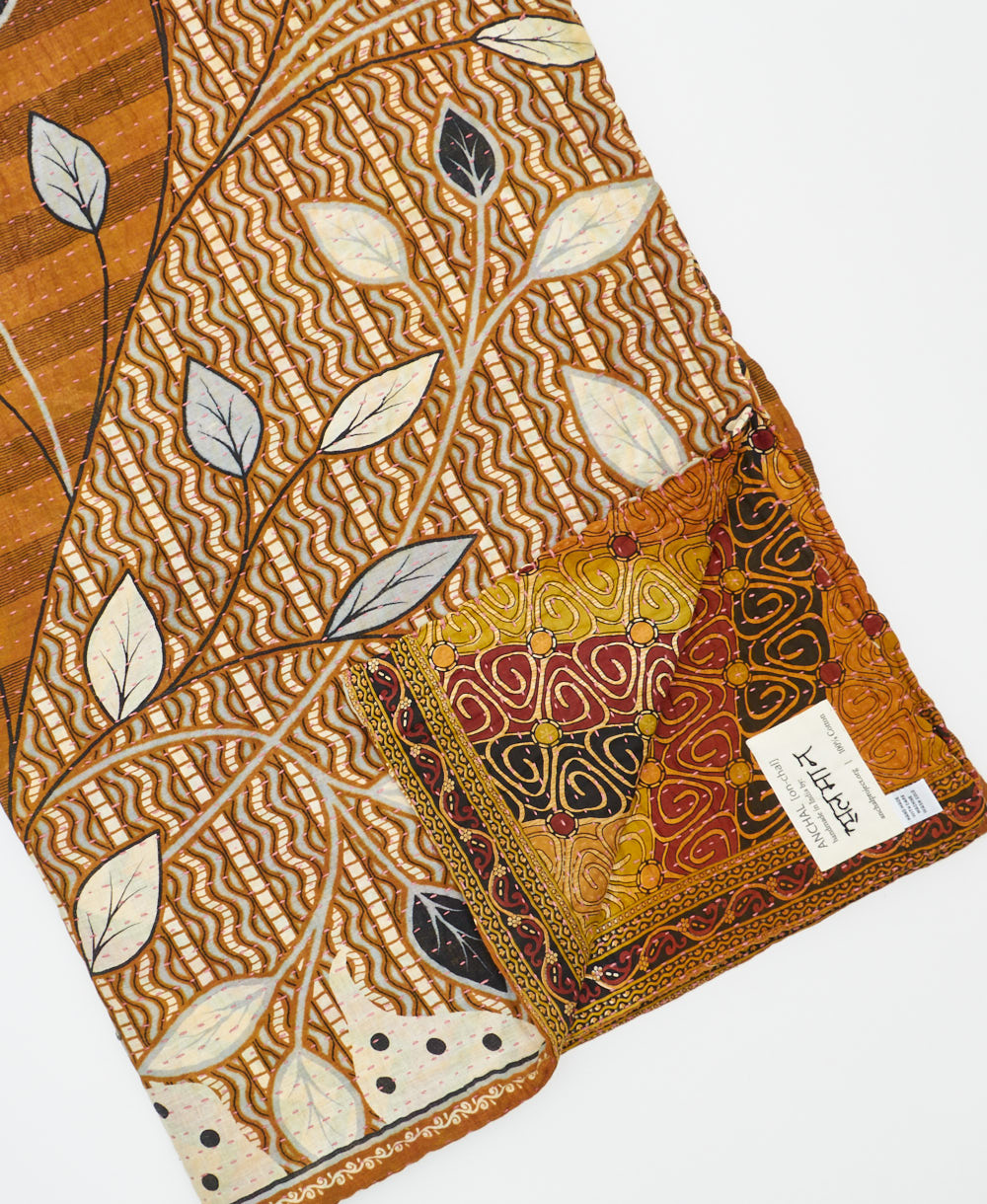 kantha quilt throw with a tag featuring the hand-stitched signature of the maker