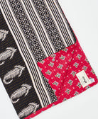 kantha quilt throw with a tag featuring the hand-stitched signature of the maker
