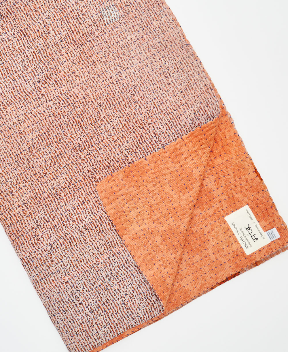 kantha quilt throw with a tag featuring the hand-stitched signature of the maker