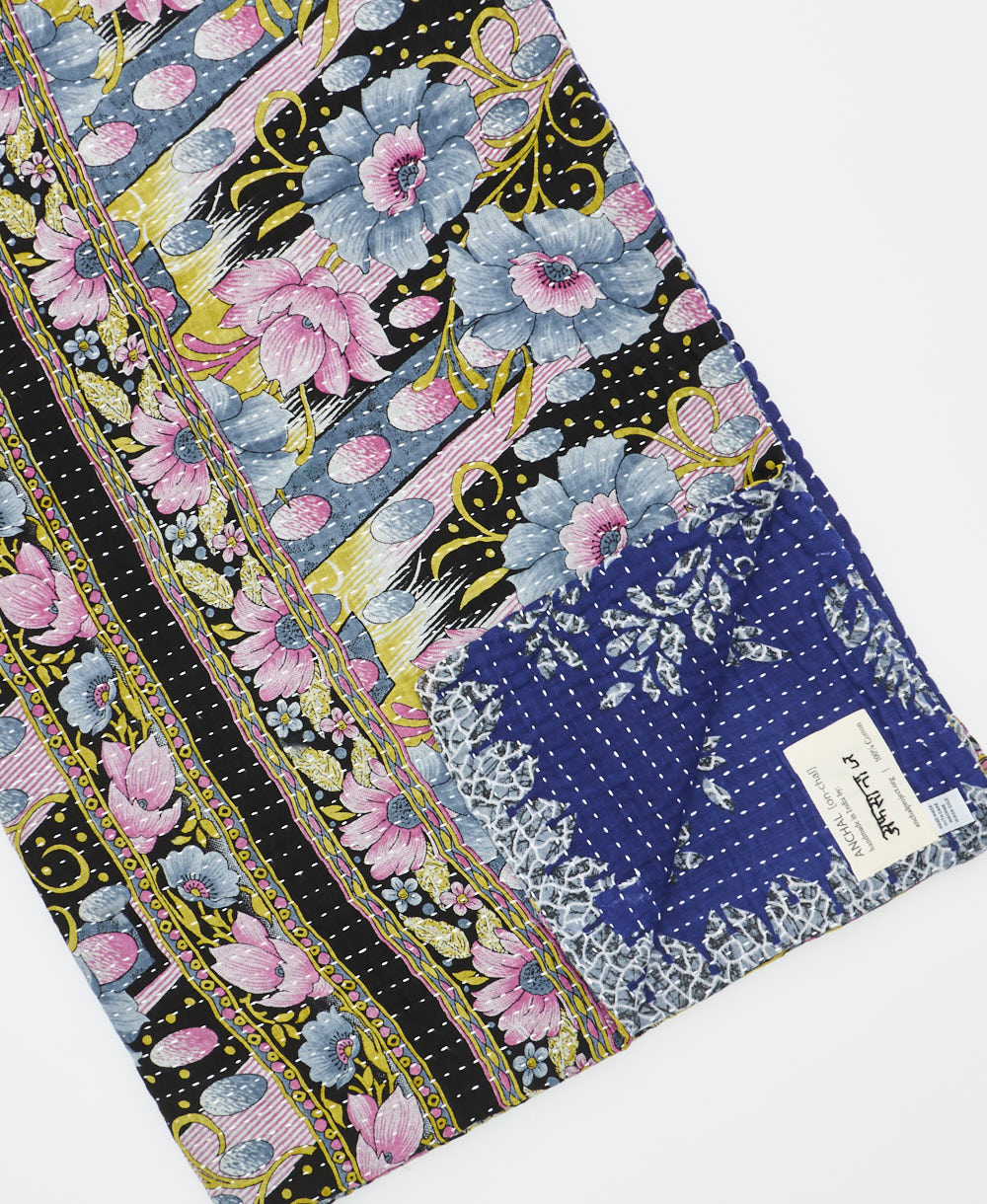 kantha quilt throw with a tag featuring the hand-stitched signature of the maker
