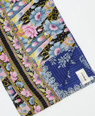kantha quilt throw with a tag featuring the hand-stitched signature of the maker