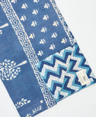 kantha quilt throw with a tag featuring the hand-stitched signature of the maker