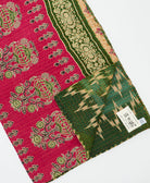 kantha quilt throw with a tag featuring the hand-stitched signature of the maker