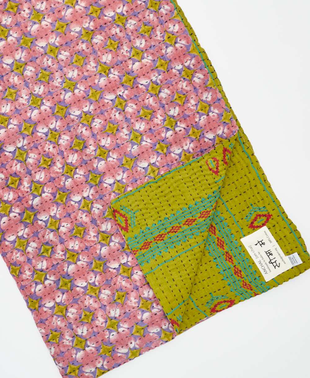 kantha quilt throw with a tag featuring the hand-stitched signature of the maker