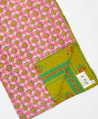 kantha quilt throw with a tag featuring the hand-stitched signature of the maker