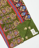 kantha quilt throw with a tag featuring the hand-stitched signature of the maker
