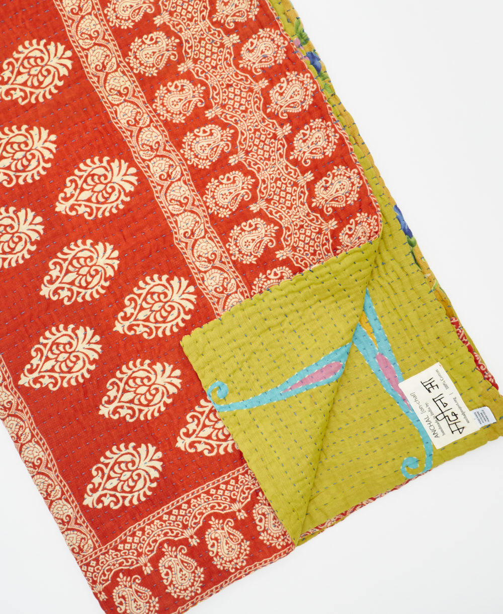 kantha quilt throw with a tag featuring the hand-stitched signature of the maker